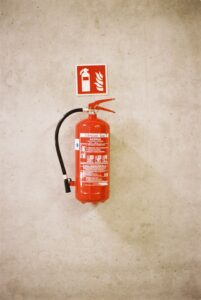 Fire extinguisher mounted on a wall with a visible sign above it.