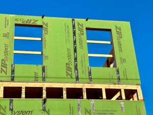 Rigid foam continuous insulation being installed over exterior wall sheathing