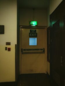 Illuminated emergency exit sign above a door in a commercial building corridor