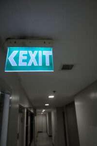 Dark commercial corridor with illuminated exit sign at the end